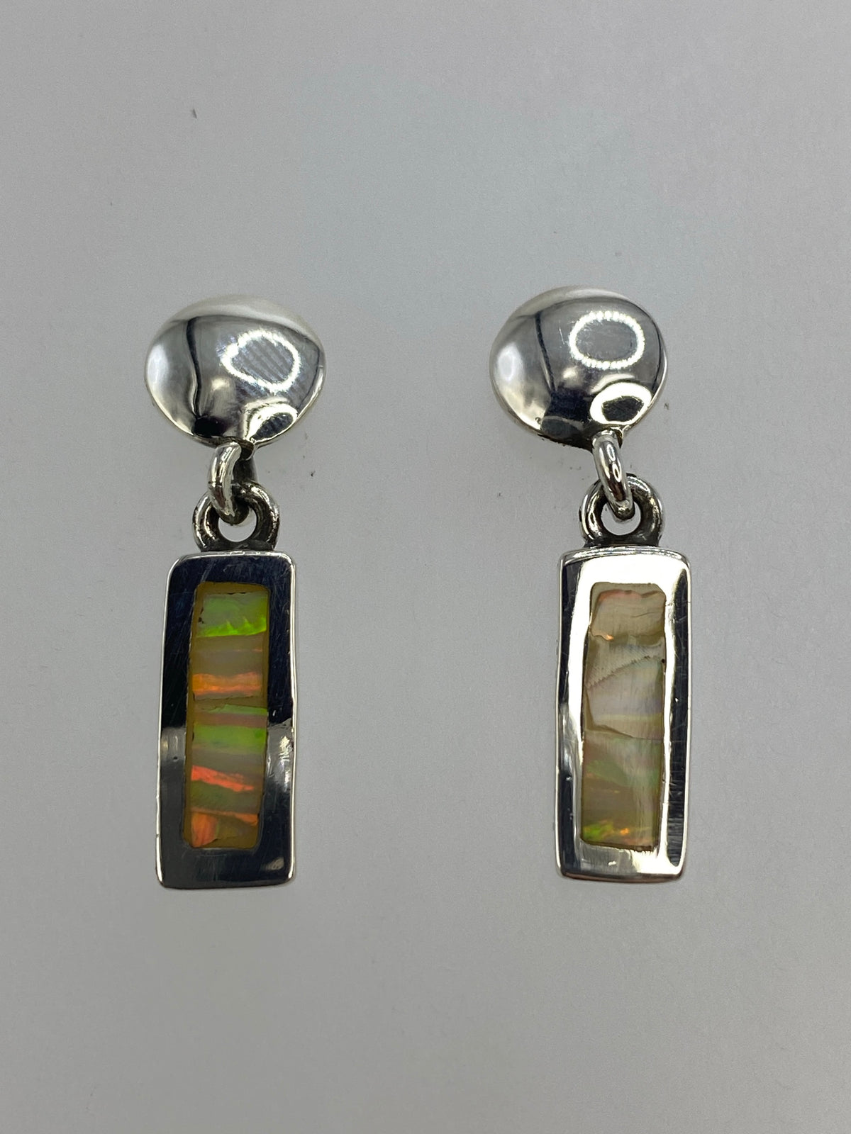 Detalle del ópalo de fuego blanco con destellos verdes y azules en arete de plata