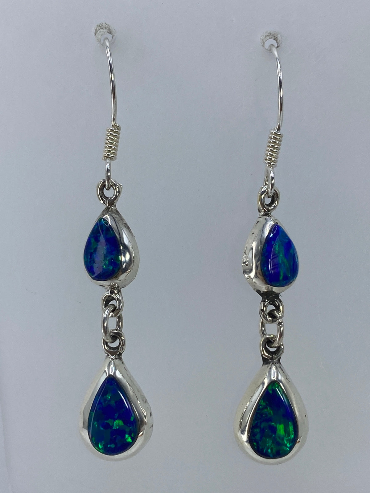 Par de aretes de plata con ópalo de fuego verde olivo engastado, sobre fondo gris