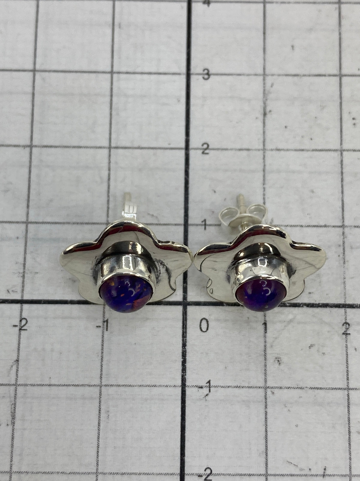 Aretes en escala comparativa sobre regla, midiendo 1.5 cm de largo
