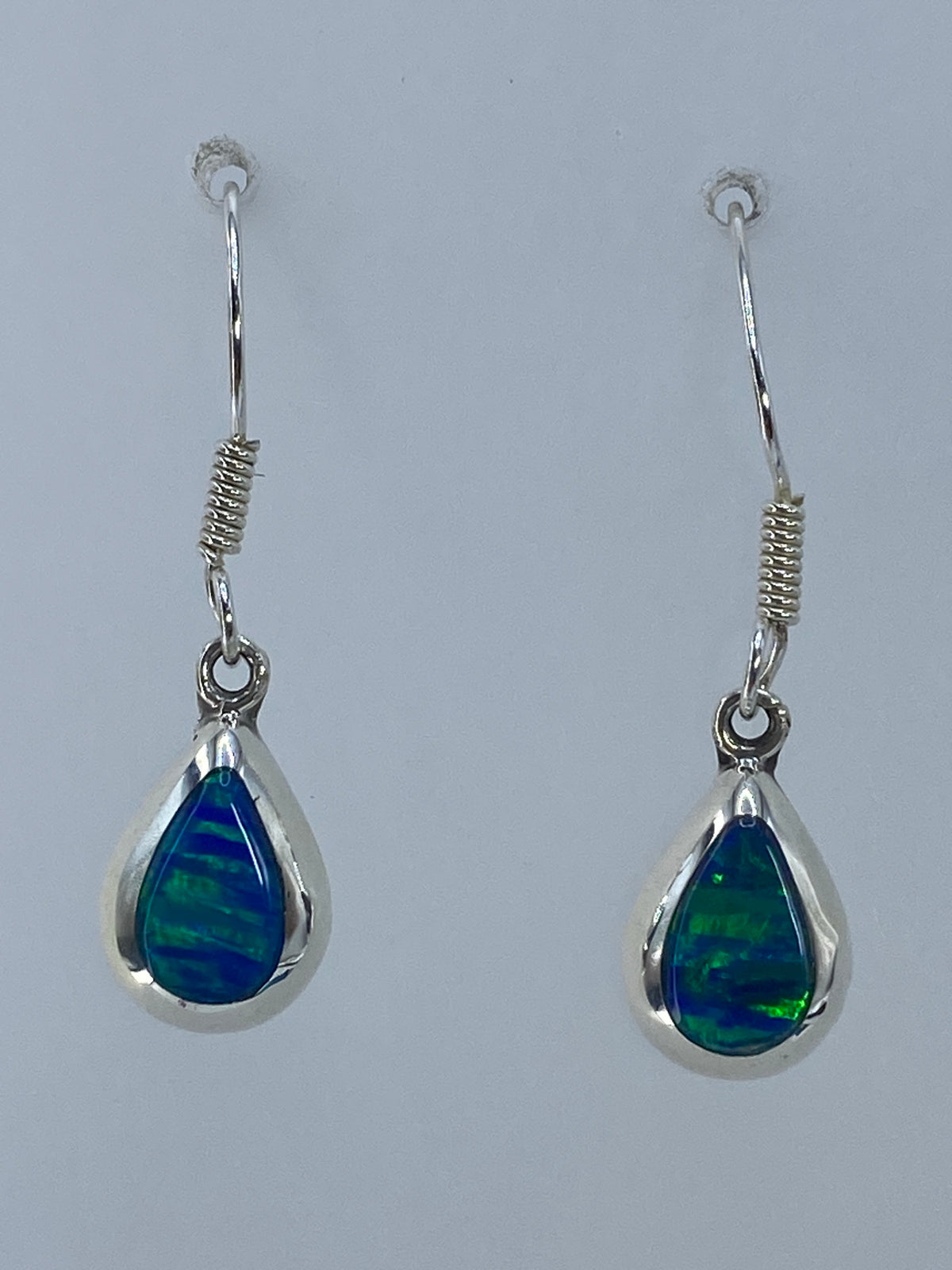 Par de aretes de plata con ópalo de fuego verde olivo colgando de los ganchos