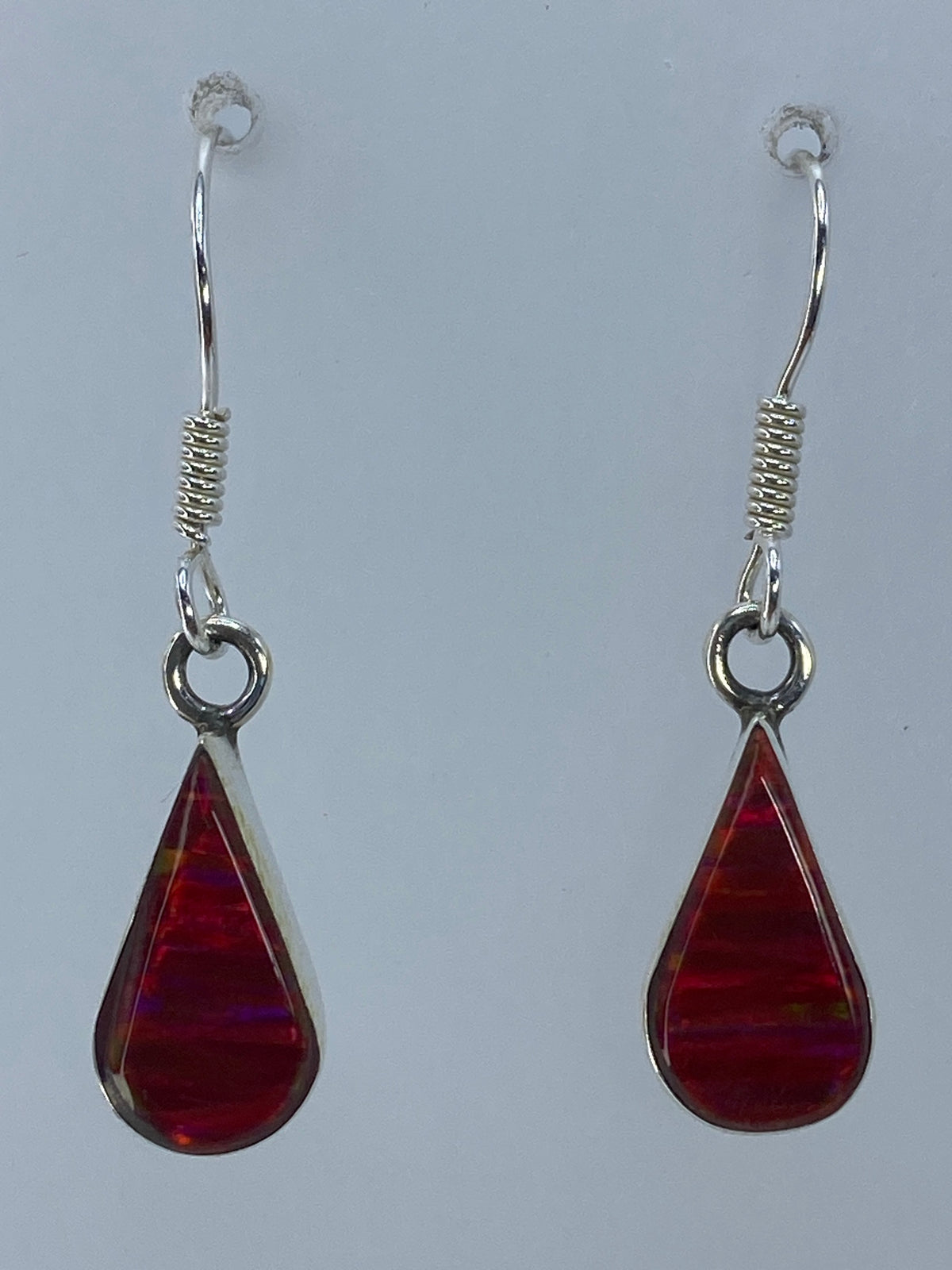 Aretes de ópalo fuego rojo sobre medidor de centímetros