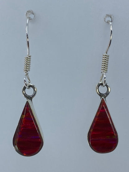 Aretes de ópalo fuego rojo sobre medidor de centímetros