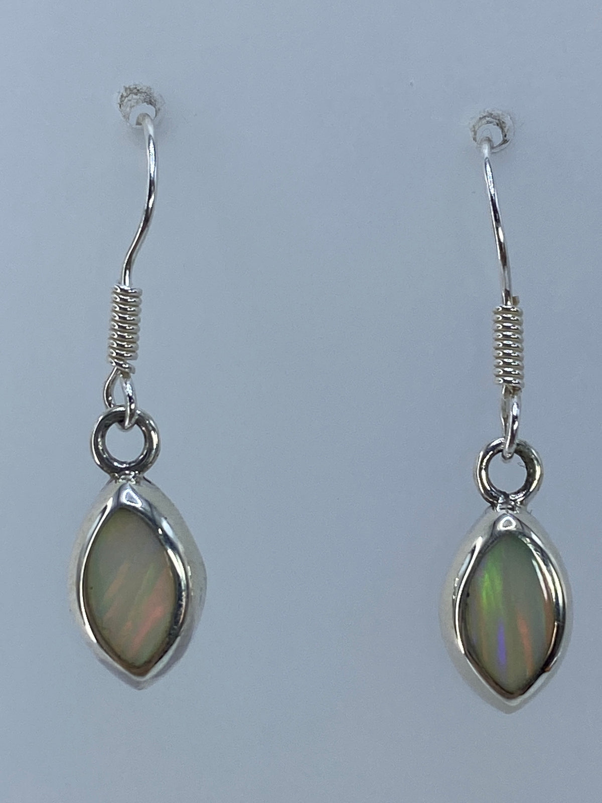 Aretes de ópalo de fuego de 2.9 cm de largo, colgando con luz natural reflejada en la piedra