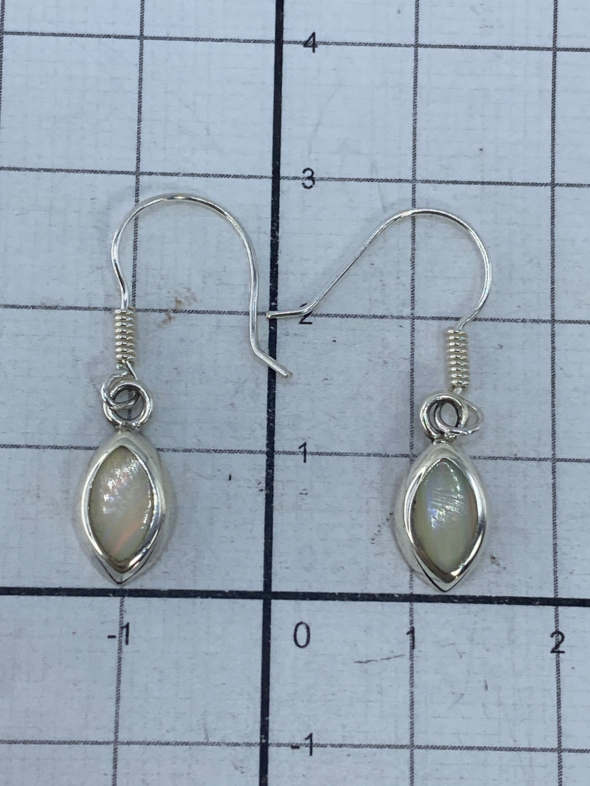 Aretes sobre escala de medida mostrando largo de 2.9 cm por pieza