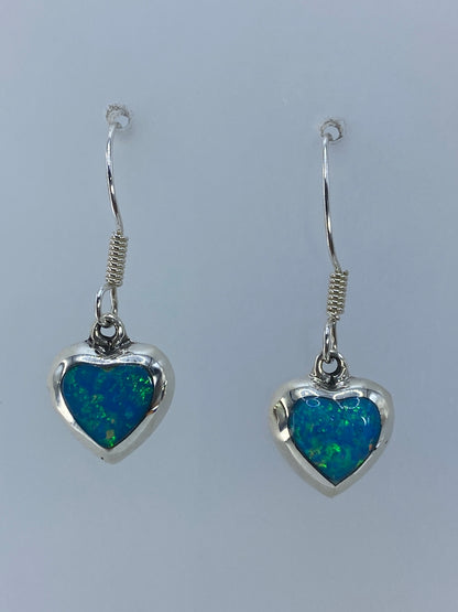 Aretes colgando mostrando el color verde olivo y reflejos del ópalo de fuego