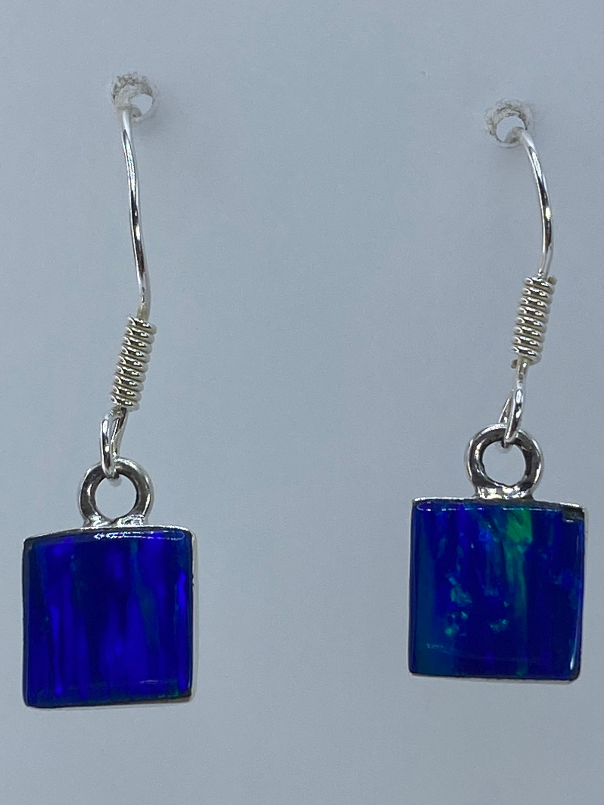 Aretes de ópalo sobre fondo blanco mostrando el brillo natural