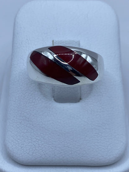 Anillo de plata con dos incrustaciones de coral rojo en la mano de una persona
