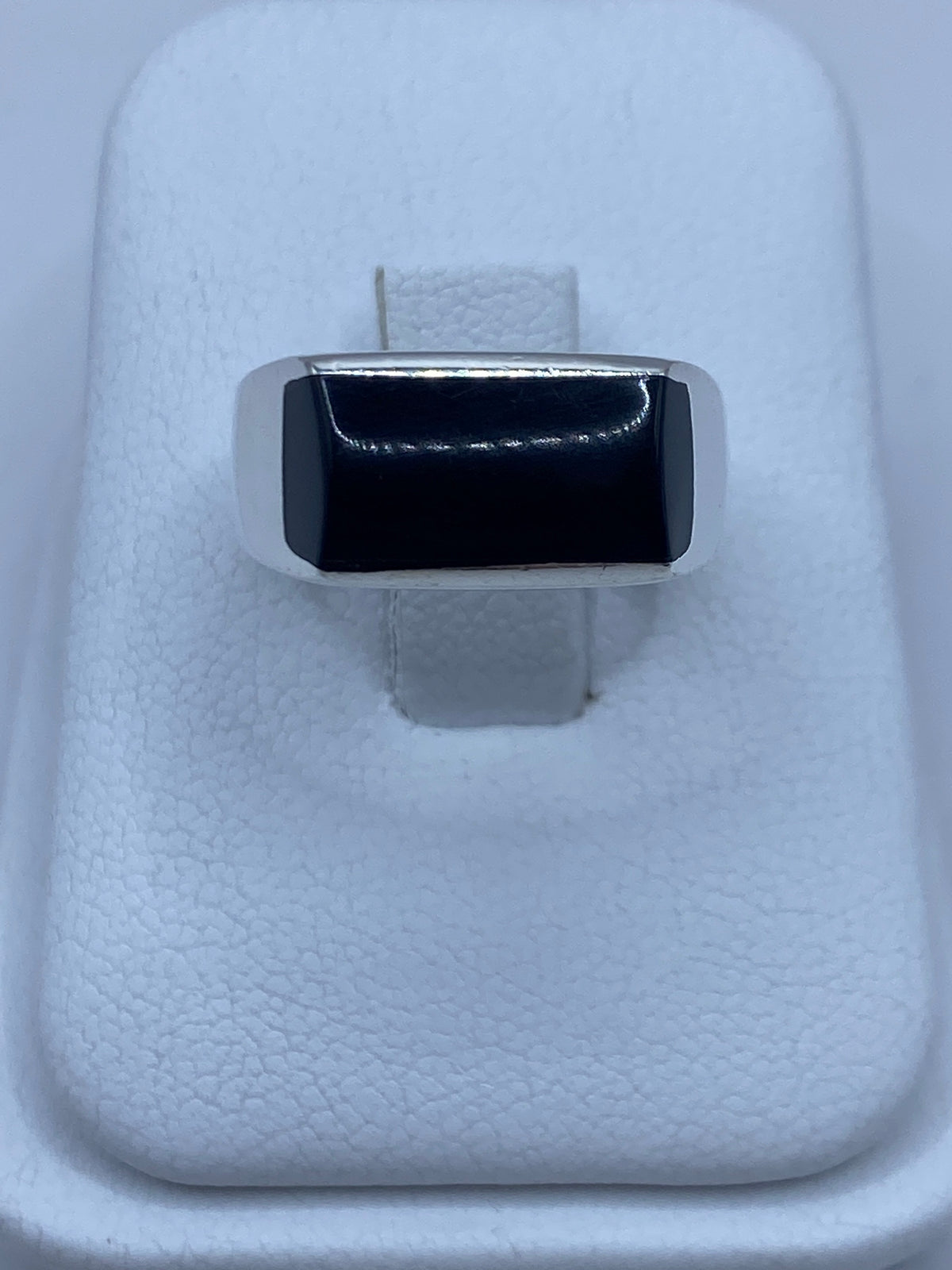 Anillo de plata con ónix negro engastado en la mano de un hombre