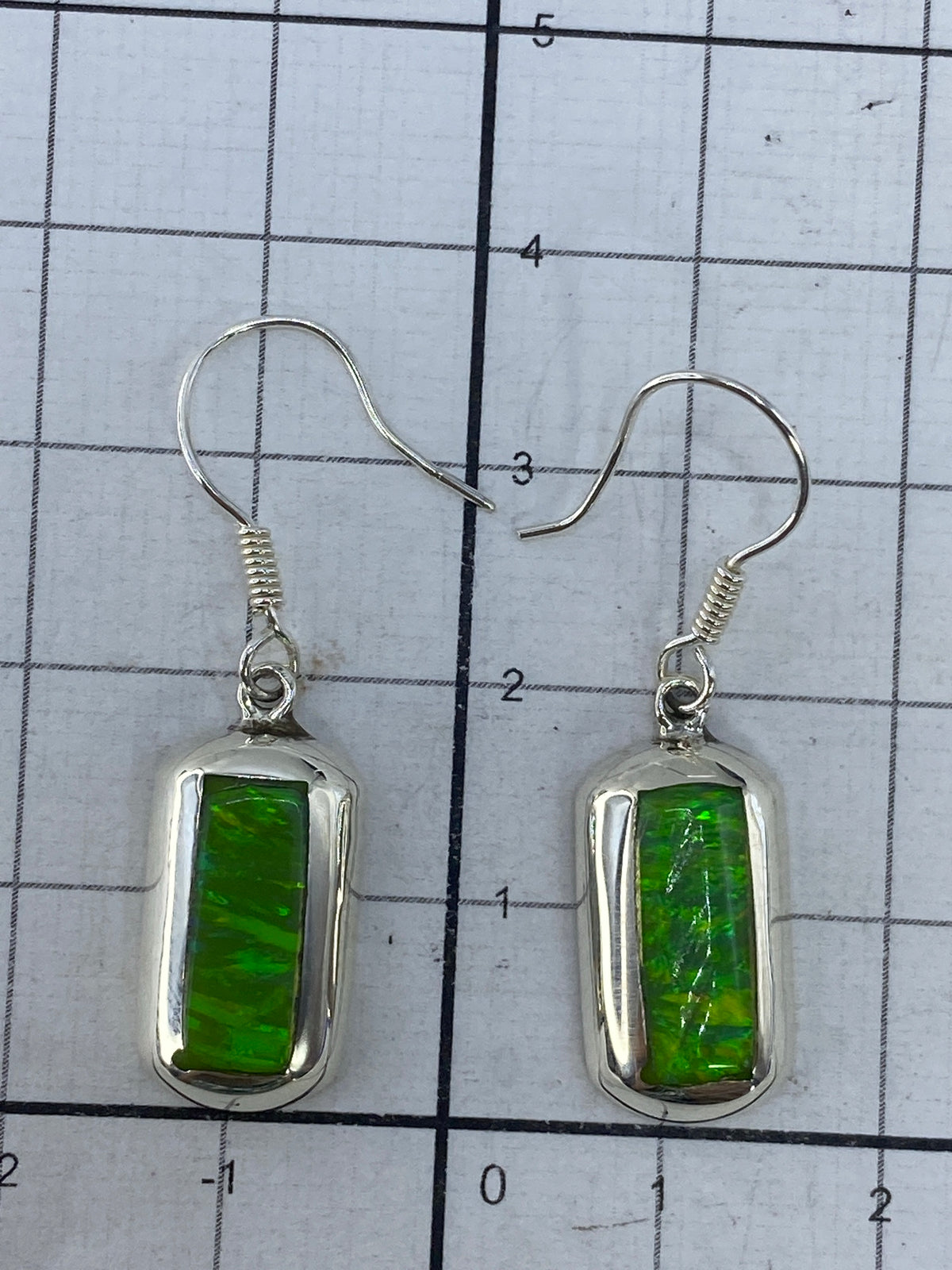 Aretes colocados junto a escala métrica mostrando 3.7 cm de largo total