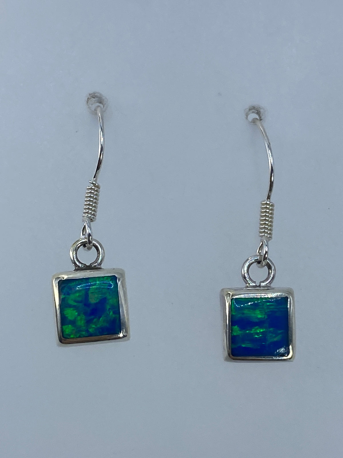 Aretes en gancho de plata mostrando el brillo del ópalo de fuego