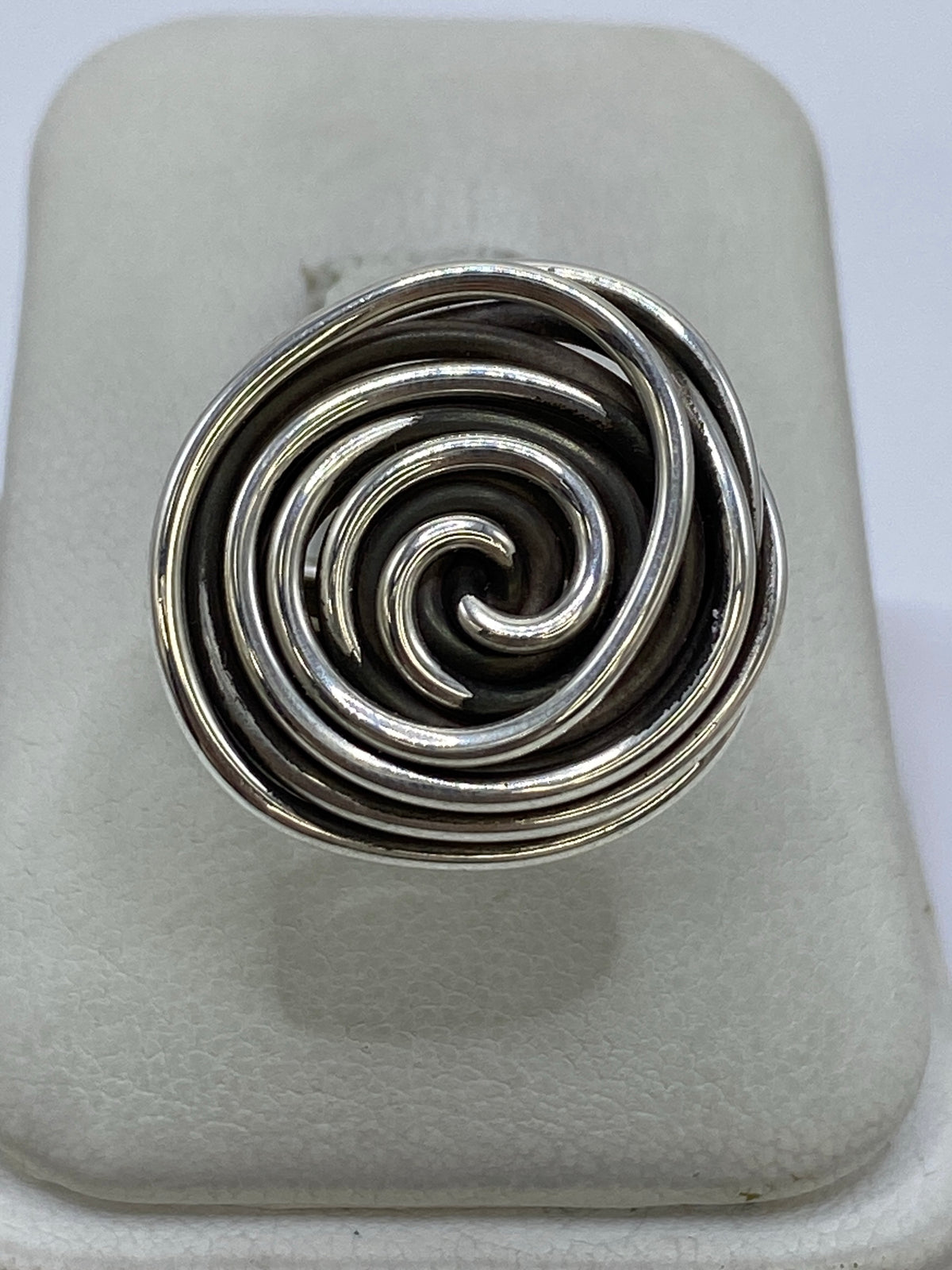 Anillo de plata con hilos giratorios en vista superior, mostrando el patrón de calado en espiral