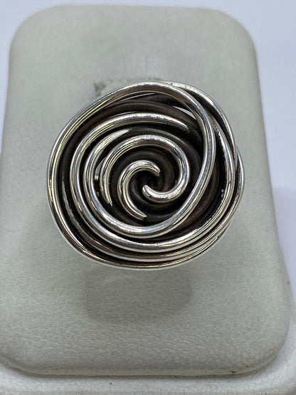 Anillo de plata con hilos giratorios en vista superior, mostrando el patrón de calado en espiral