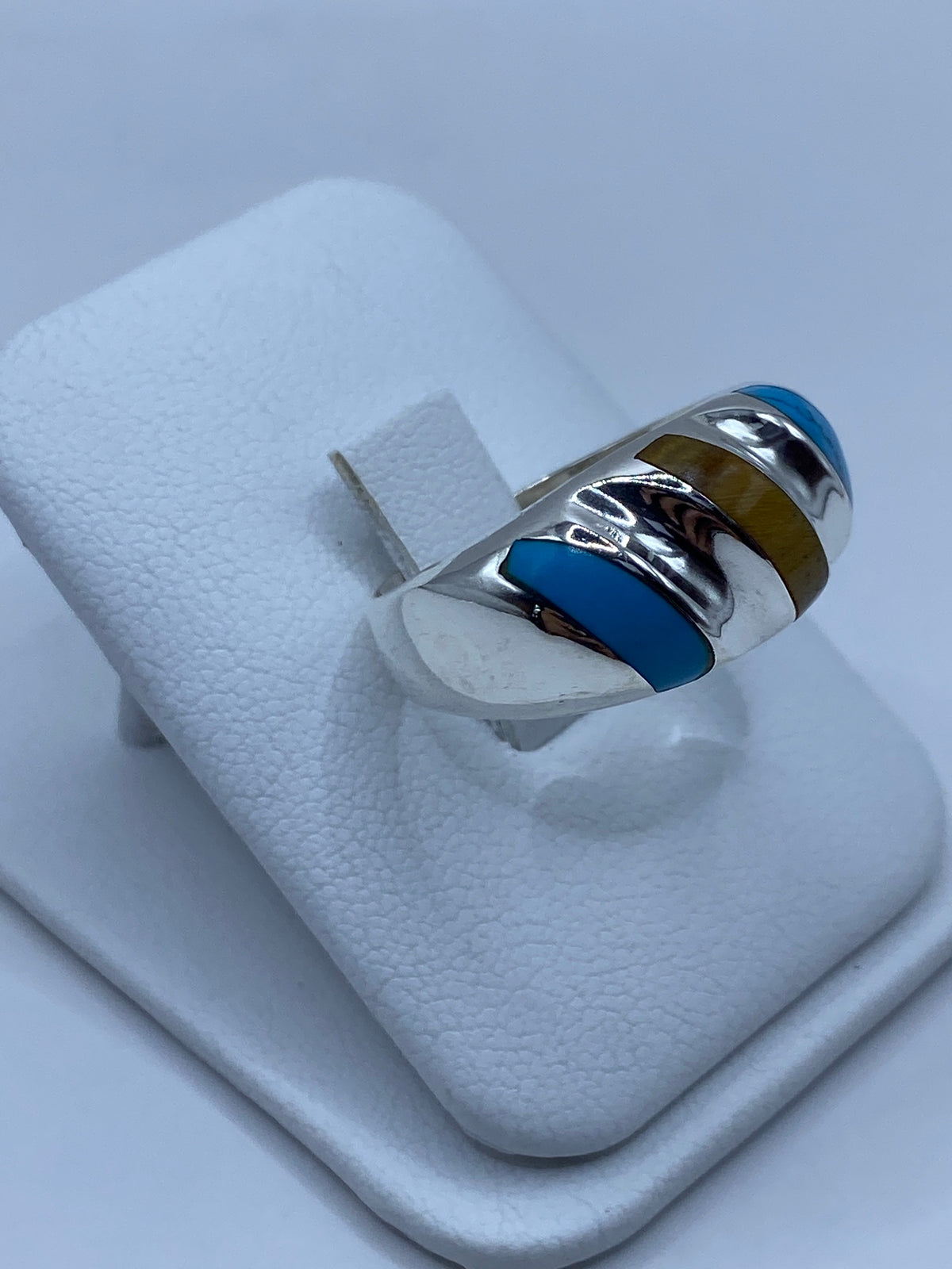 Detalle lateral del anillo mostrando el engaste de turquesa y las bandas de plata