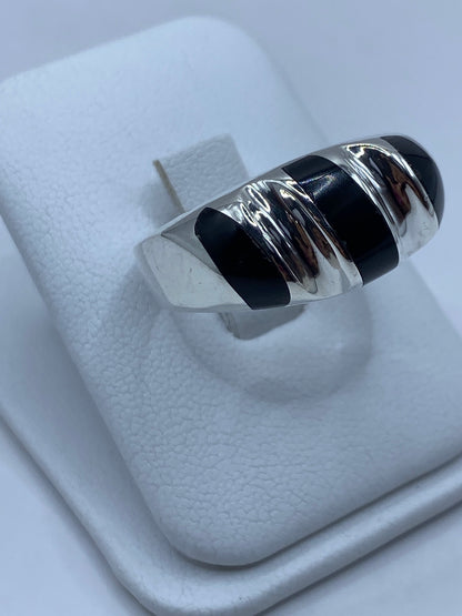 Anillo de ónix y plata puesto en dedo, mostrando el contraste de la piedra negra y la plata pulida