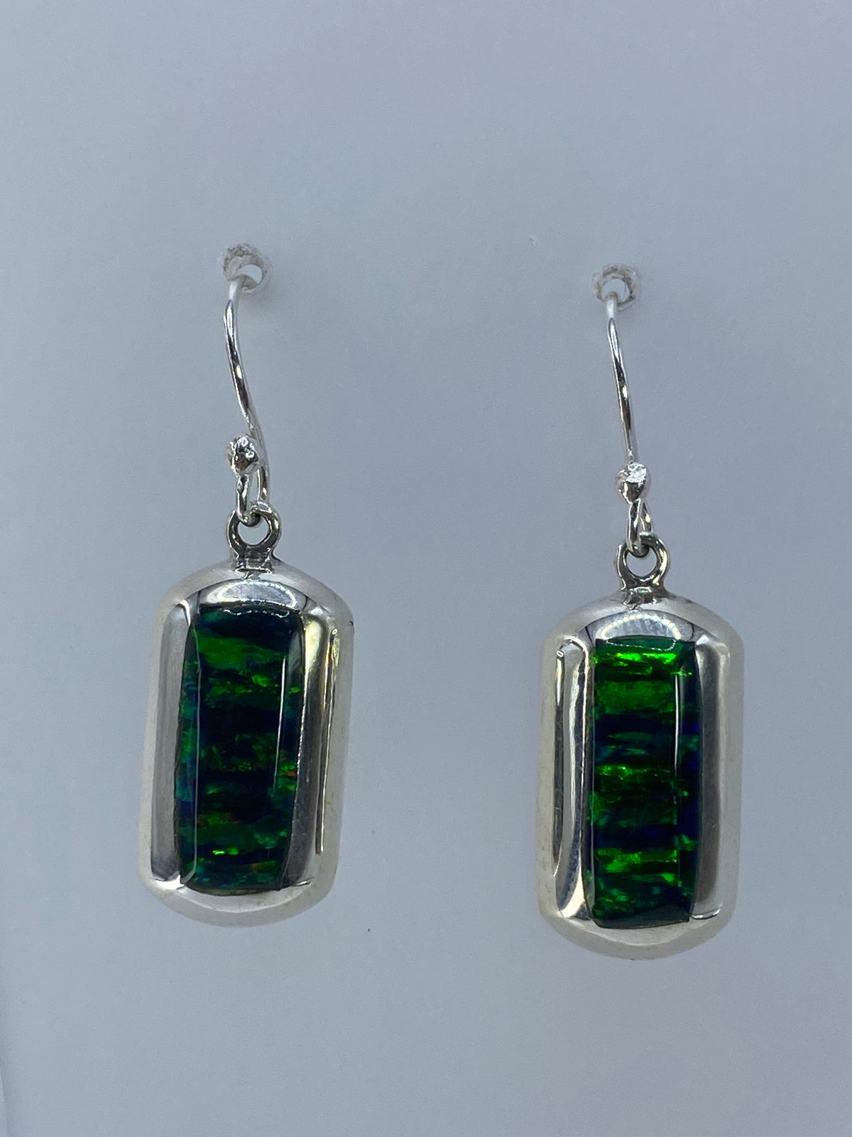 Detalle de los aretes mostrando el ópalo de fuego verde translúcido en el cilindro de plata