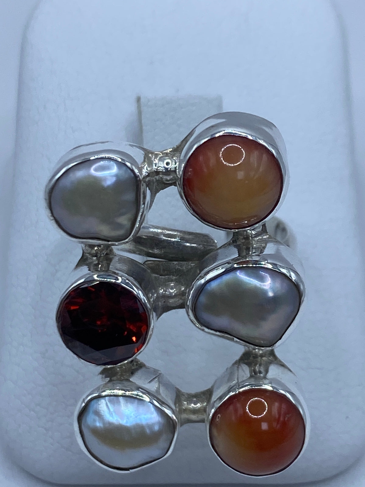 Anillo ajustable de plata con perla iridiscente y circonia roja engastadas a mano