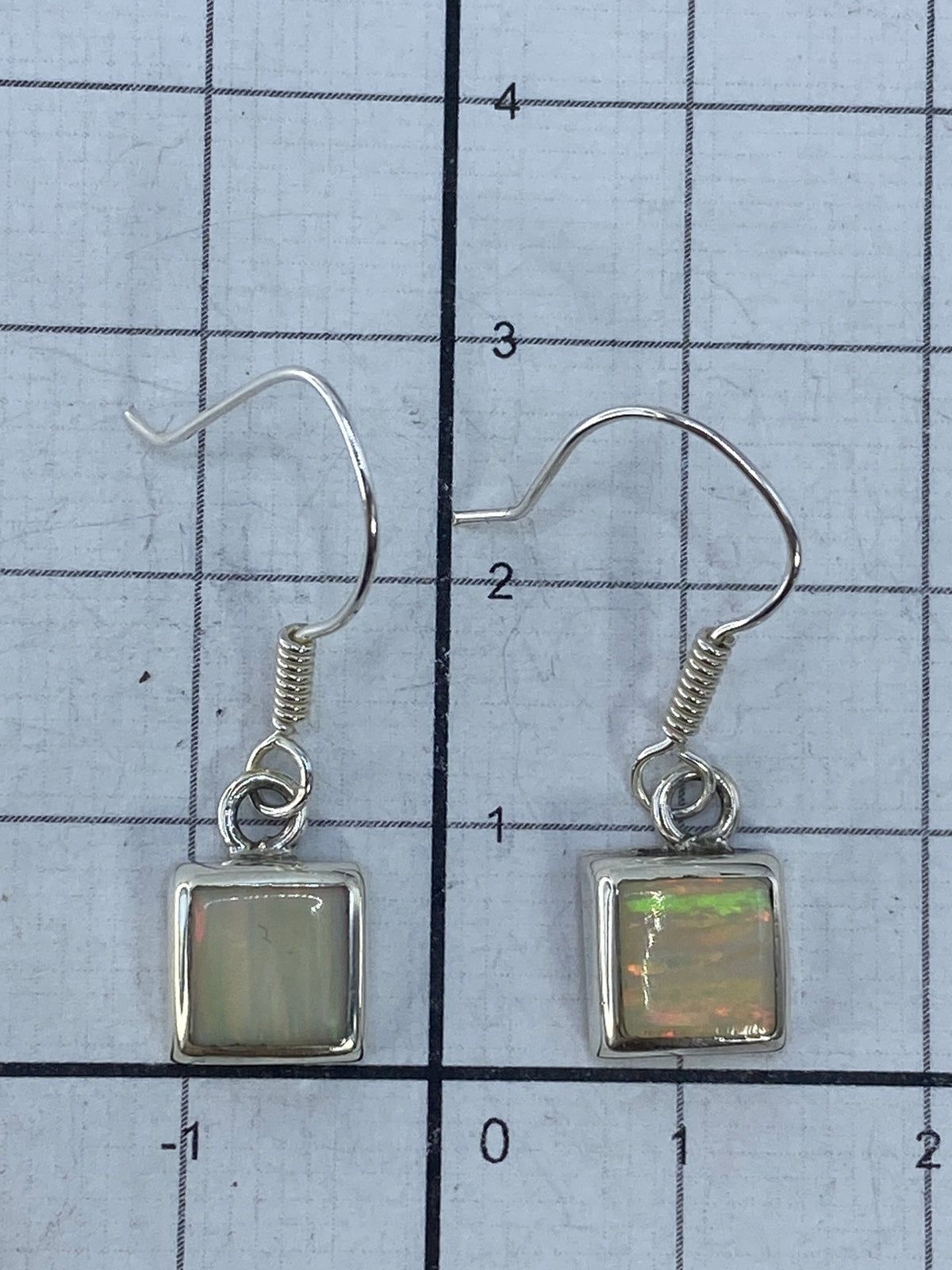 Aretes de ópalo de fuego sobre fondo blanco midiendo 2.7 cm de largo
