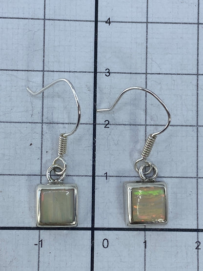Aretes de ópalo de fuego sobre fondo blanco midiendo 2.7 cm de largo