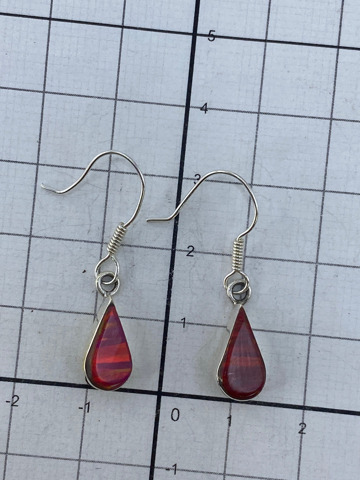 Los dos aretes sobre fondo blanco con su engaste de piedra visible