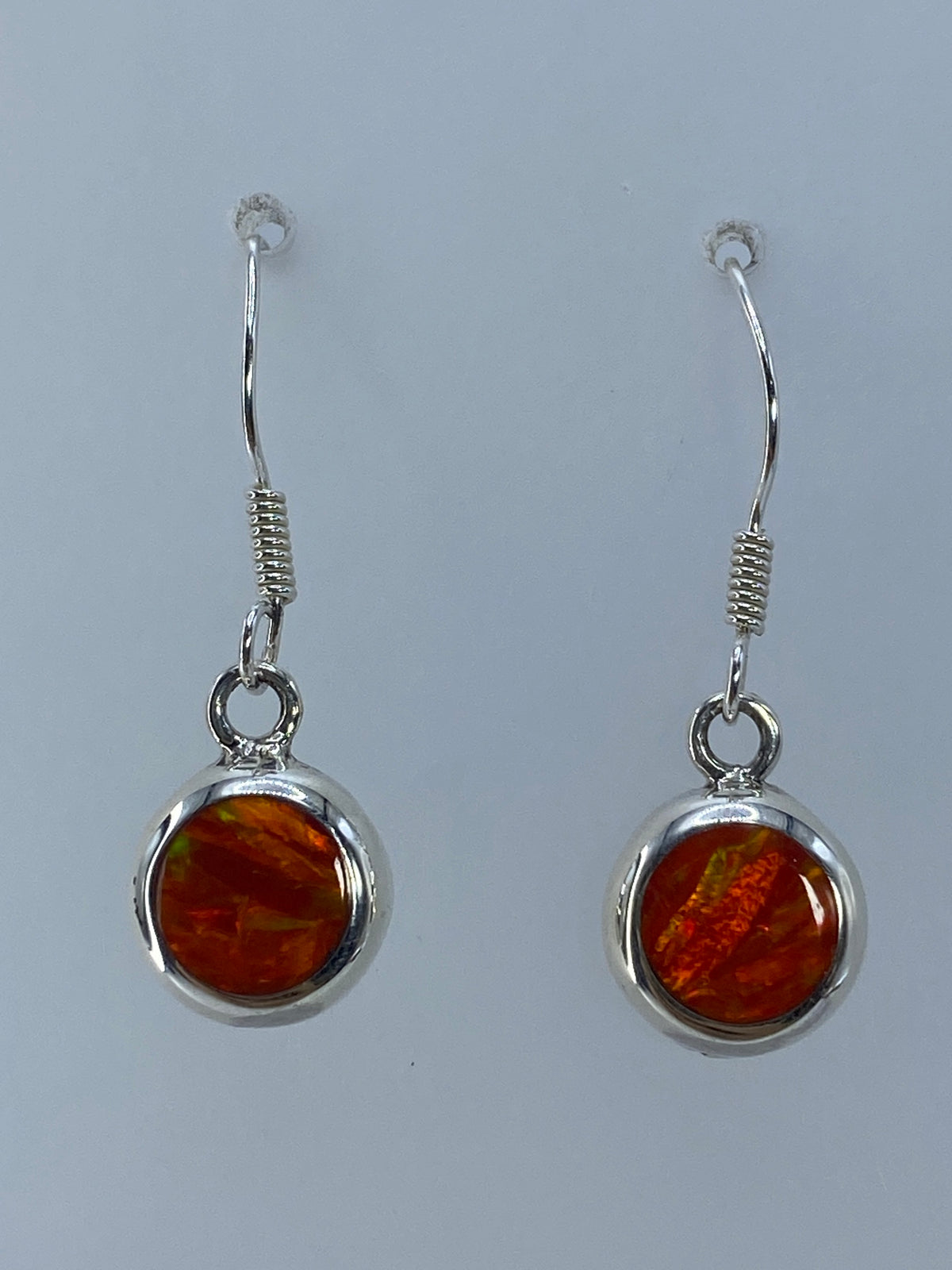 Detalle del engaste de ópalo de fuego en cilindro de plata, mostrando el brillo naranja y reflejos dorados
