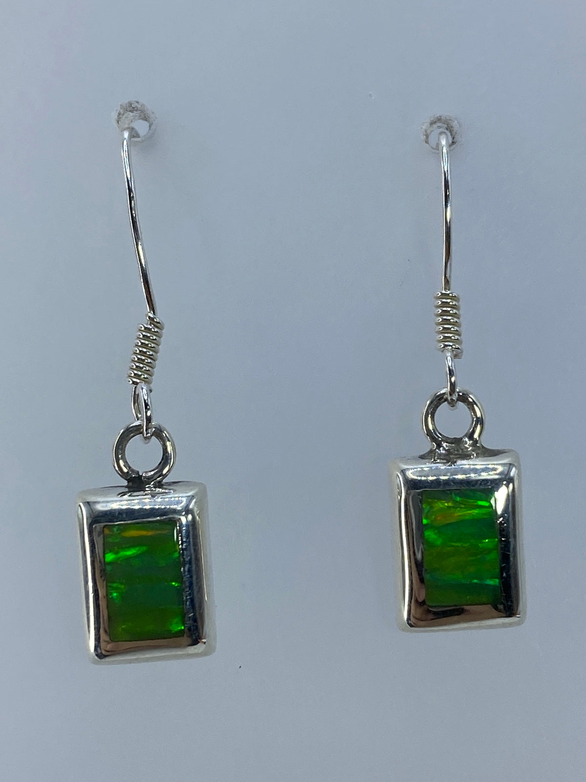 Par de aretes de plata con ópalo de fuego verde olivo engastados a mano, colgando del gancho