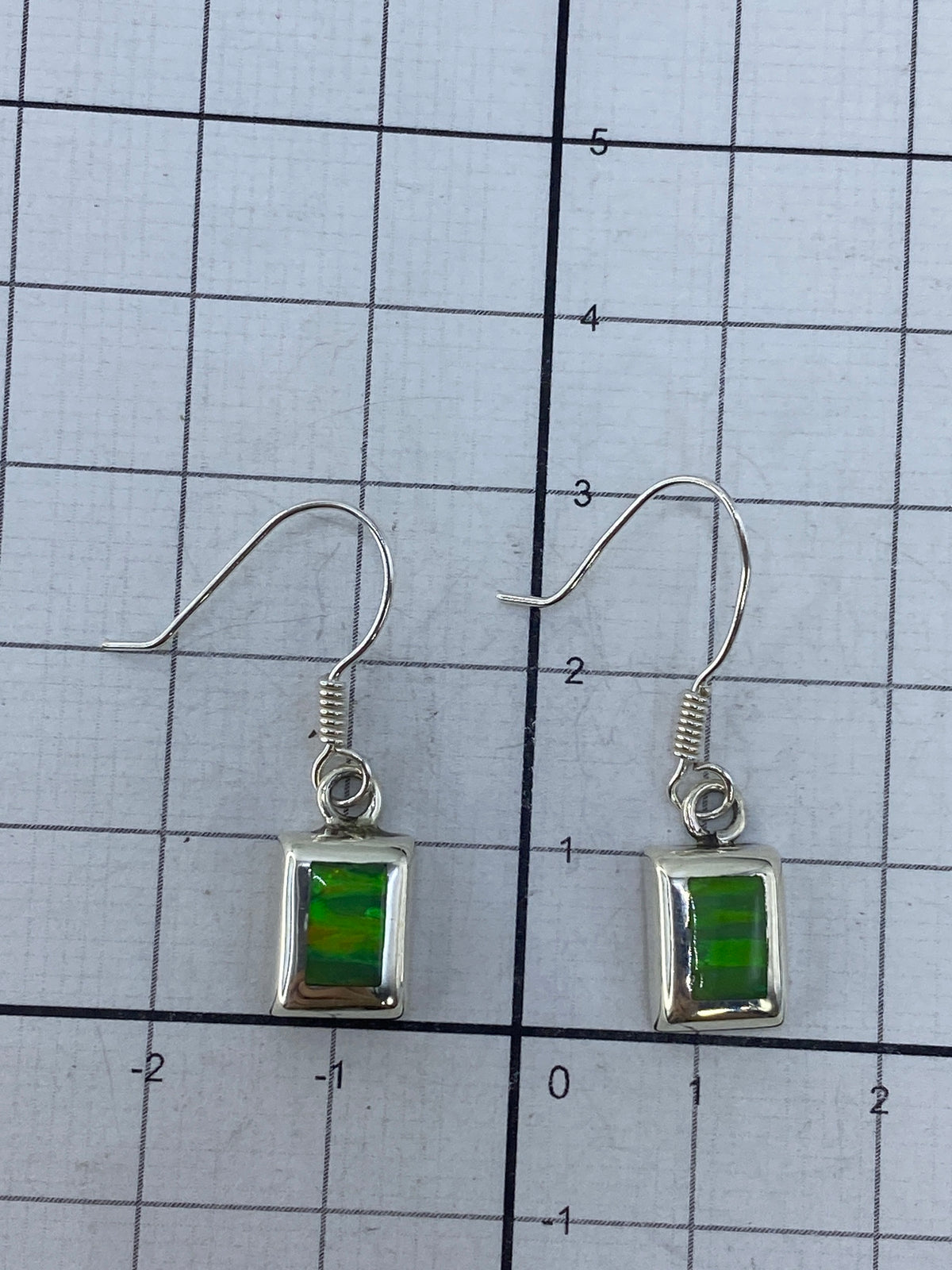 Aretes sobre fondo gris mostrando el Quinto 925 y el trabajo de incrustación a mano