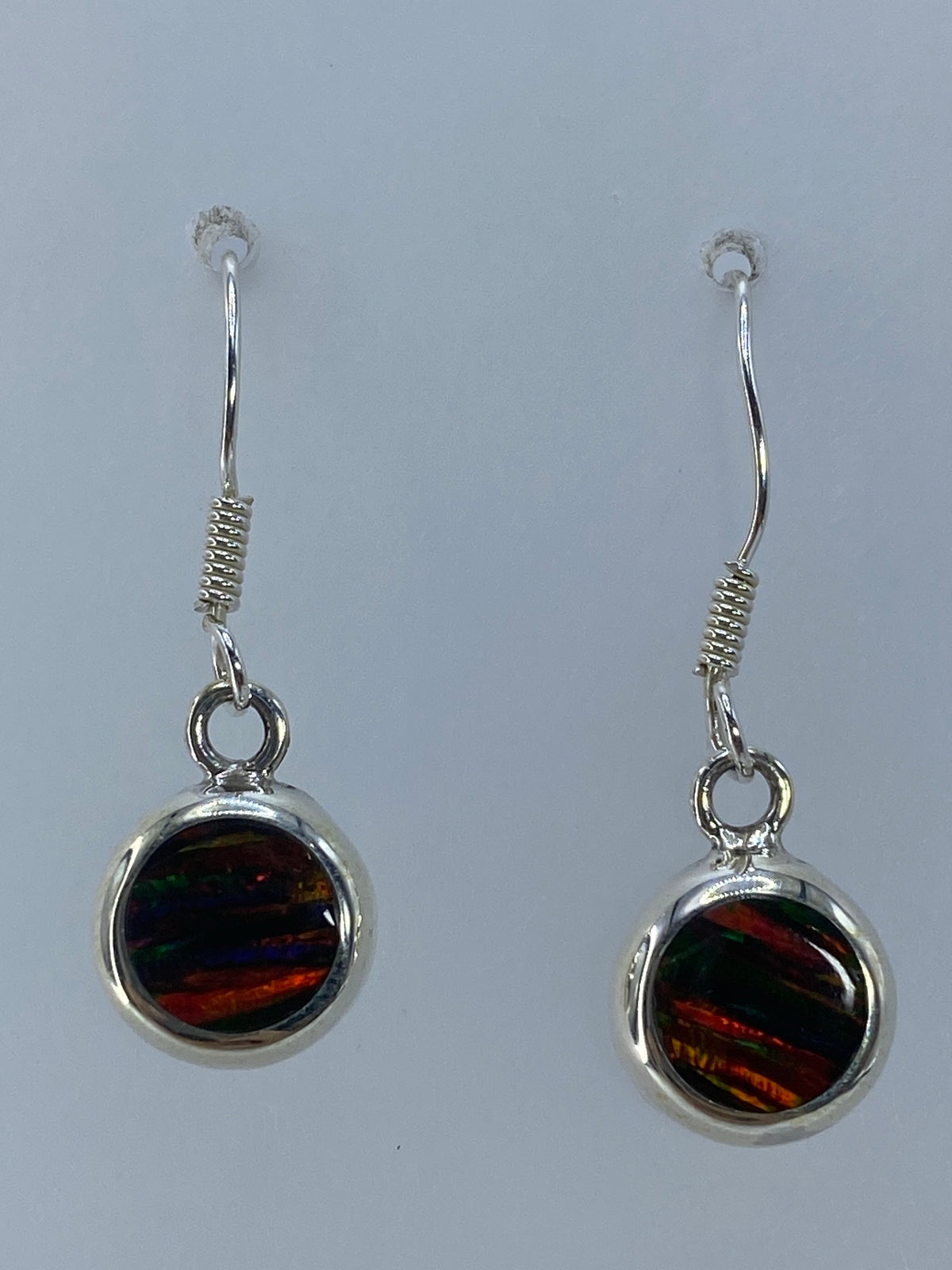Par de aretes de plata con ópalo de fuego multicolor reflejando tonos rojos, naranjas y dorados