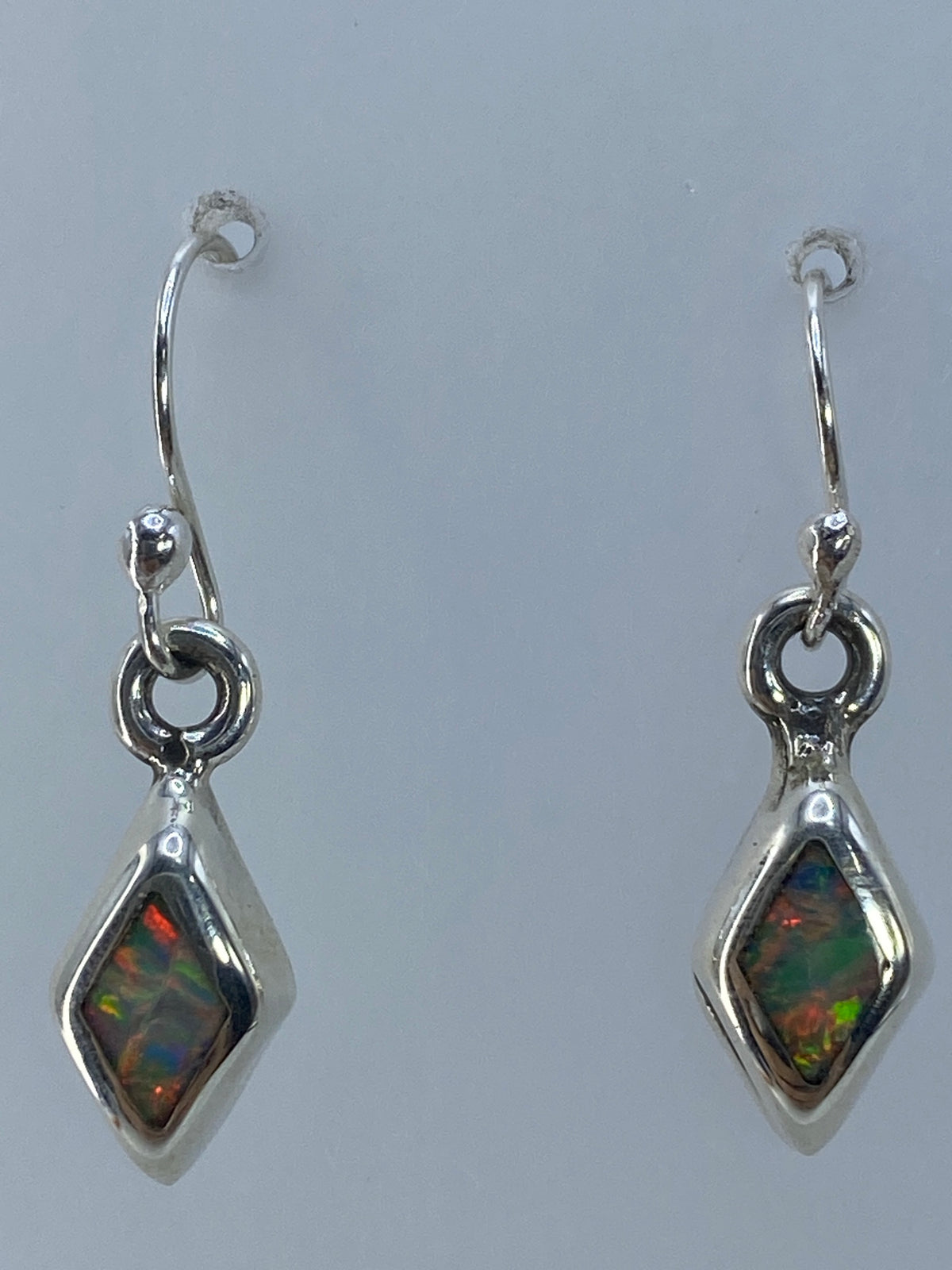 Aretes de ópalo de fuego colgando, luz reflejada en los destellos del mineral