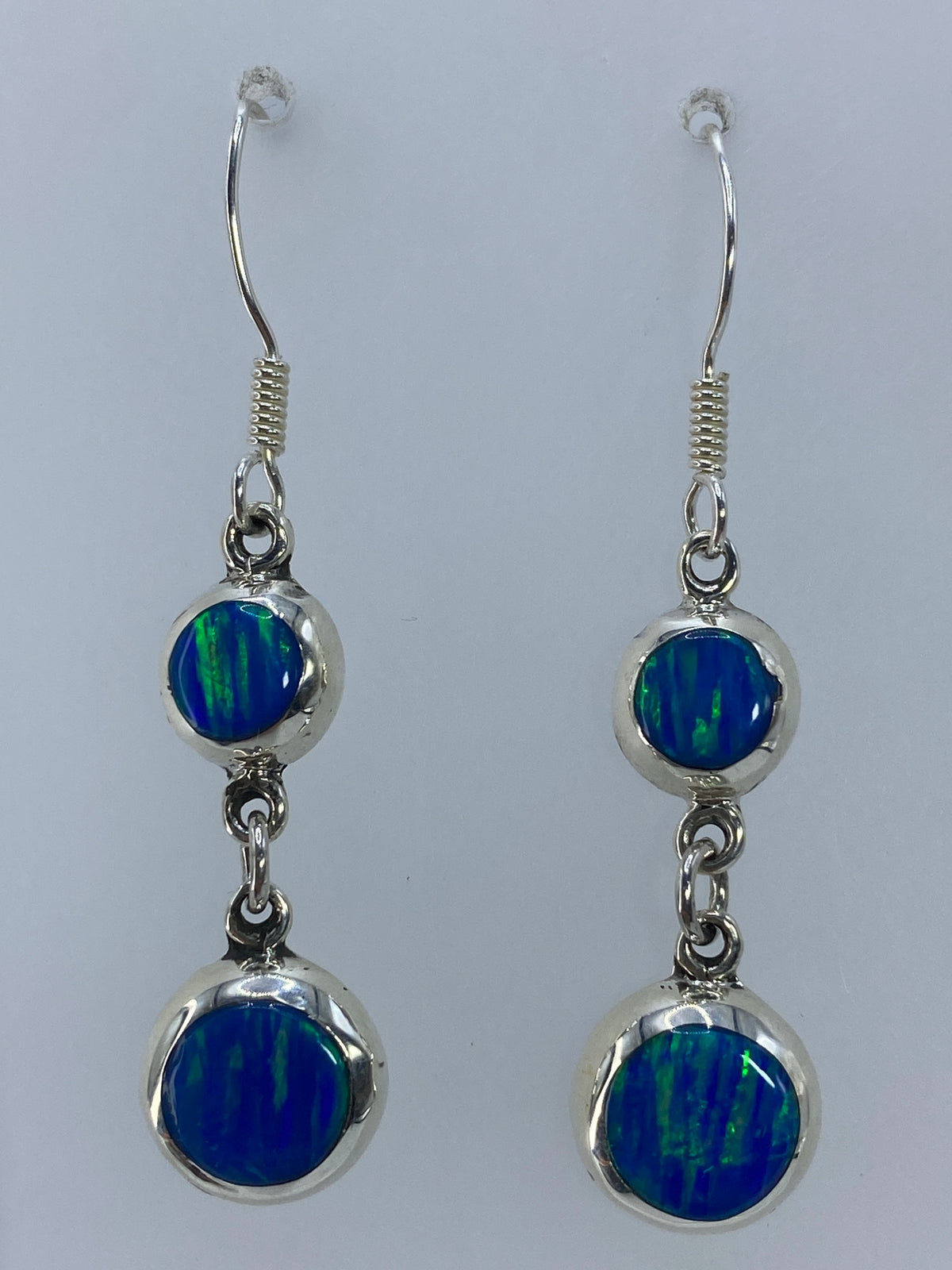 Aretes de plata con ópalo de fuego verde olivo, destellos visibles en la piedra engastada