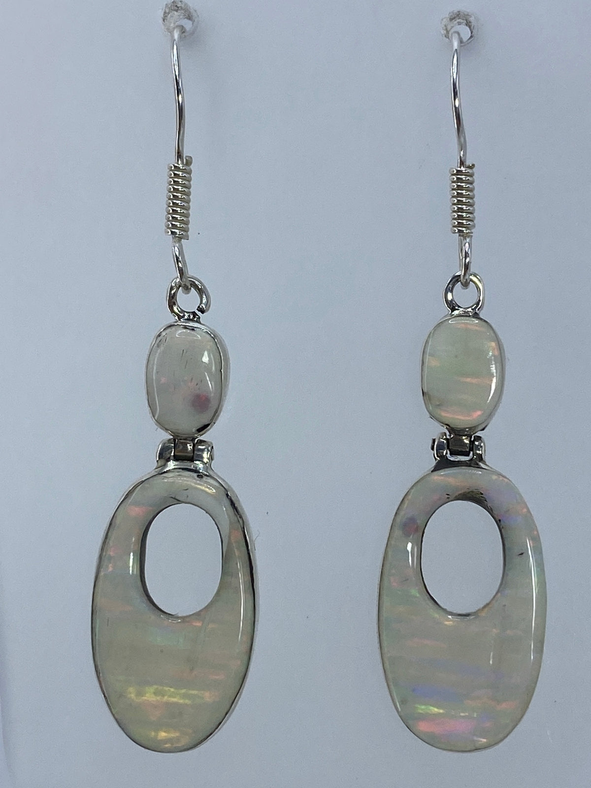 Par de aretes de plata 925 con ópalo de fuego multicolor colgando de un gancho de plata