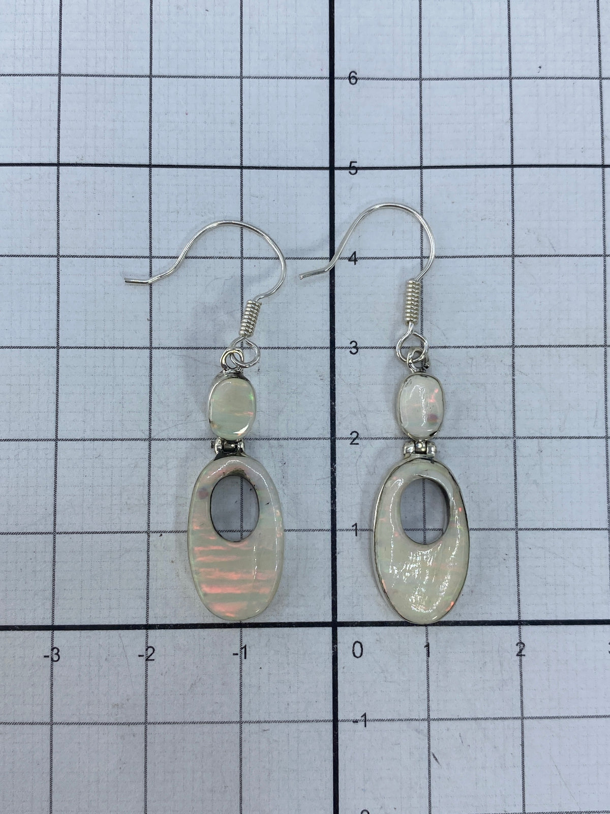 Aretes de plata con ópalo de fuego sobre escala con hallmark 925 visible