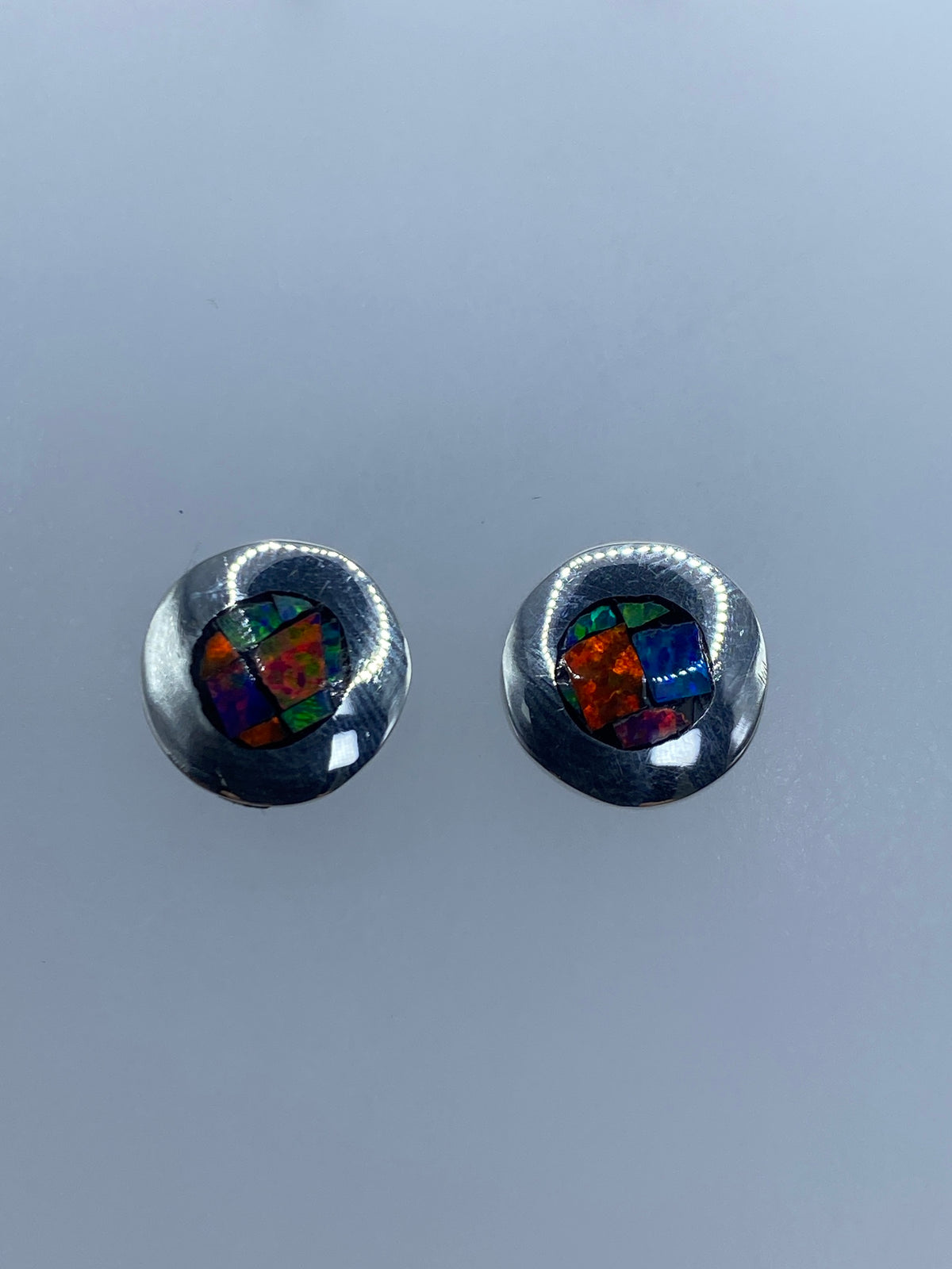 Par de aretes de plata con ópalo de fuego multicolor engastado, visto de frente