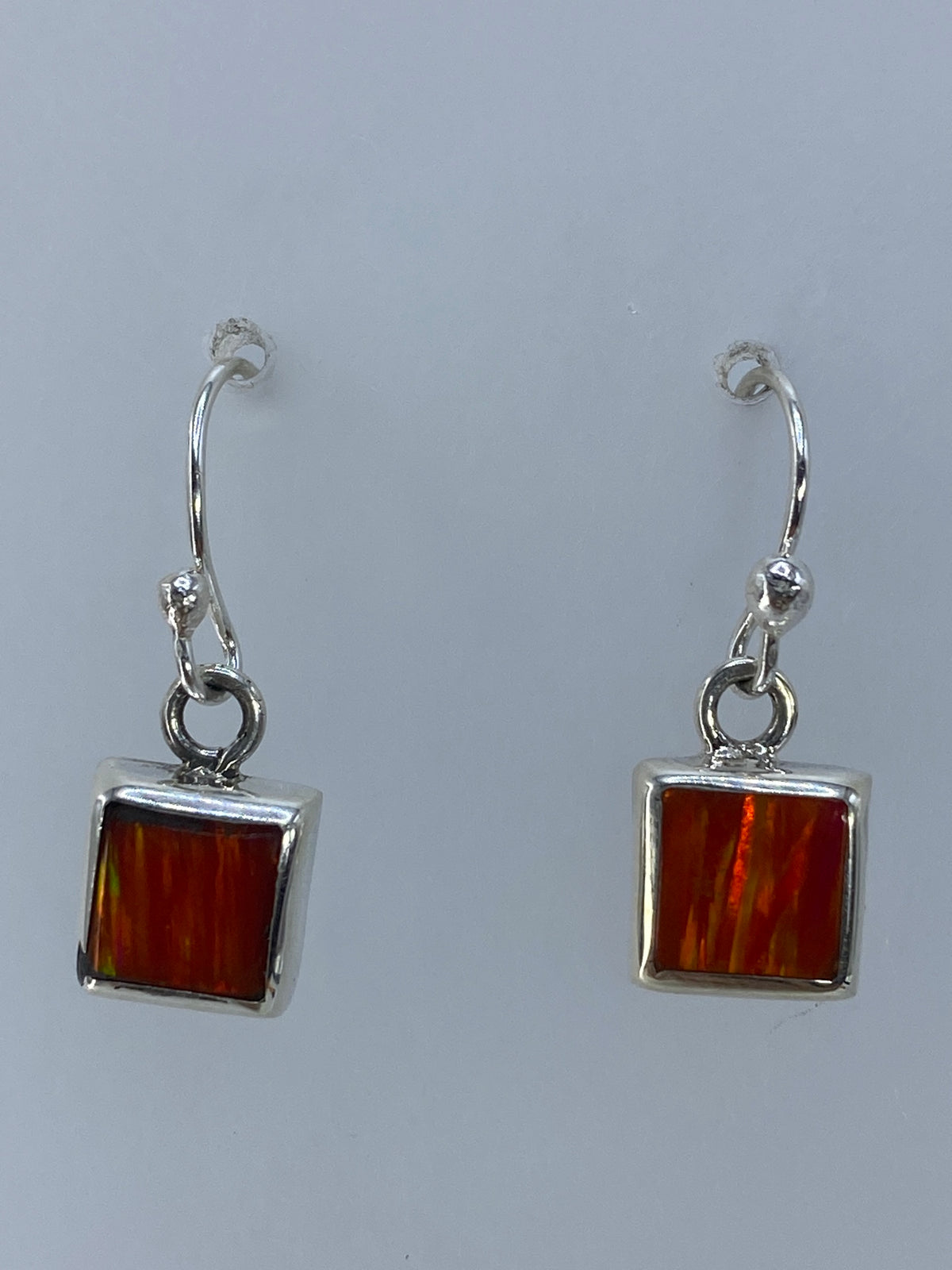 Par de aretes de plata con ópalo de fuego naranja, colgando de un alambre