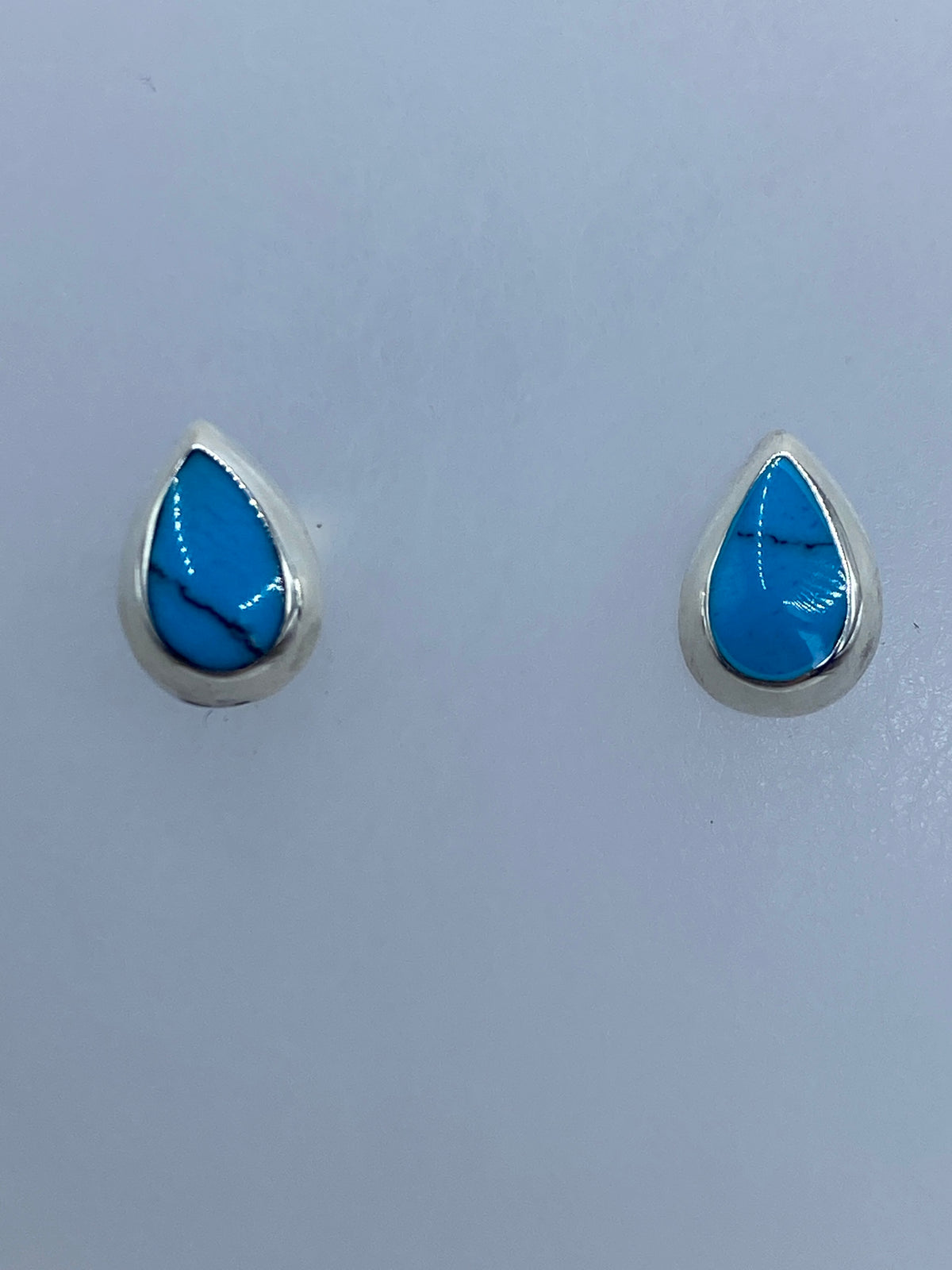 Aretes de turquesa sobre regla métrica mostrando tamaño de 0.9 cm