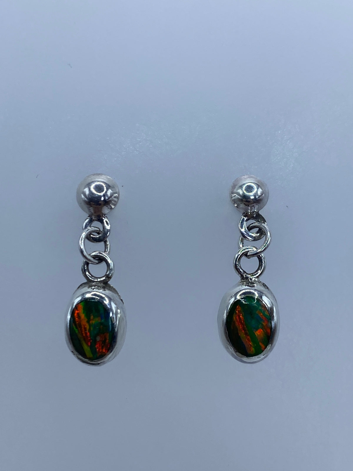 Par de aretes de plata 925 con ópalo de fuego multicolor engastado, mostrados de frente