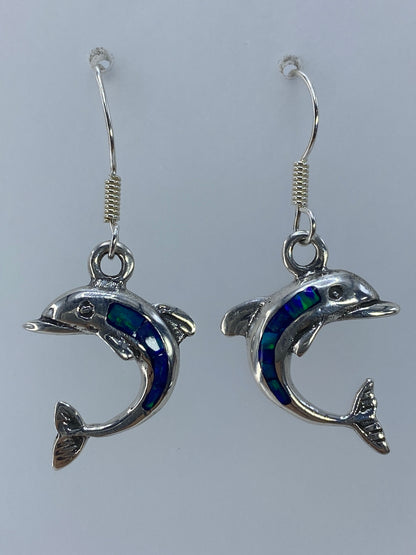 Detalle de los dos delfines plateados mostrando el engaste a mano del ópalo verde olivo