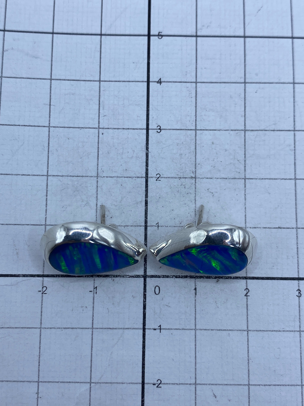 Aretes sobre fondo gris mostrando el brillo del ópalo azul y el Quinto 925