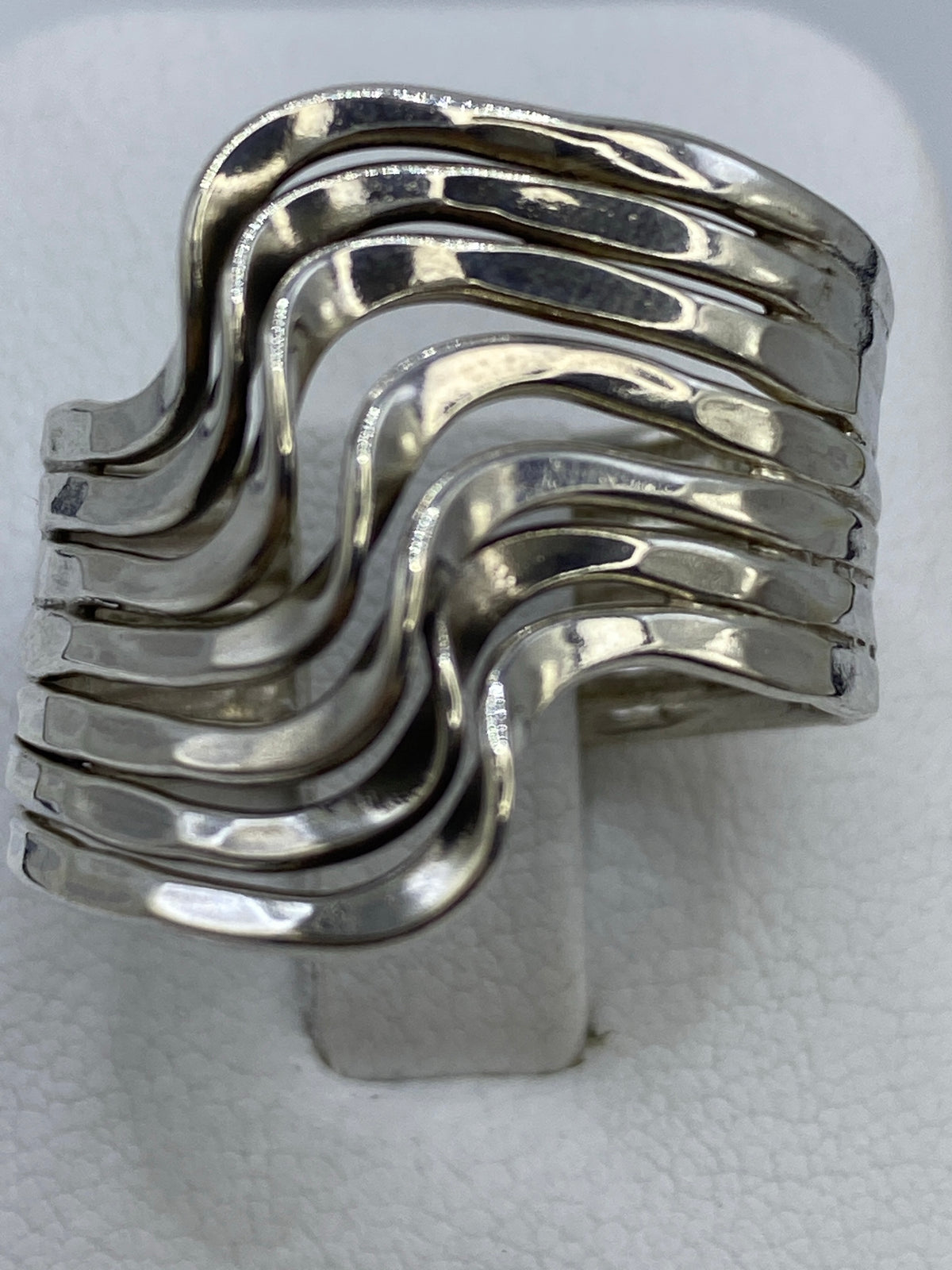 Anillo de plata repujado con ondas asimétricas en la mano de una mujer
