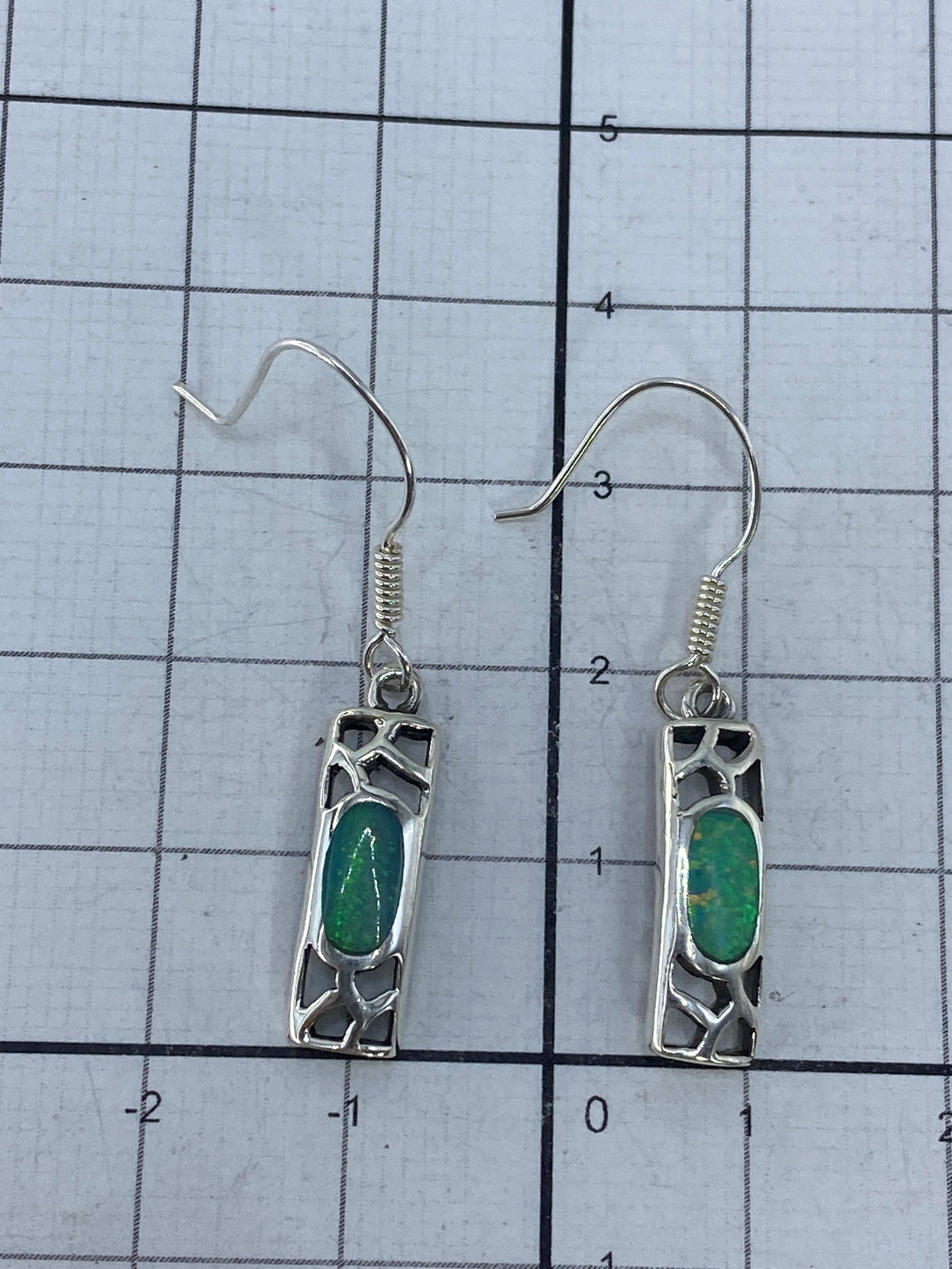 Aretes sobre fondo neutro con gancho de plata visible