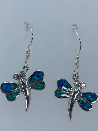 Aretes colgando mostrando el largo de 3.3 cm y el movimiento de la luz en el ópalo