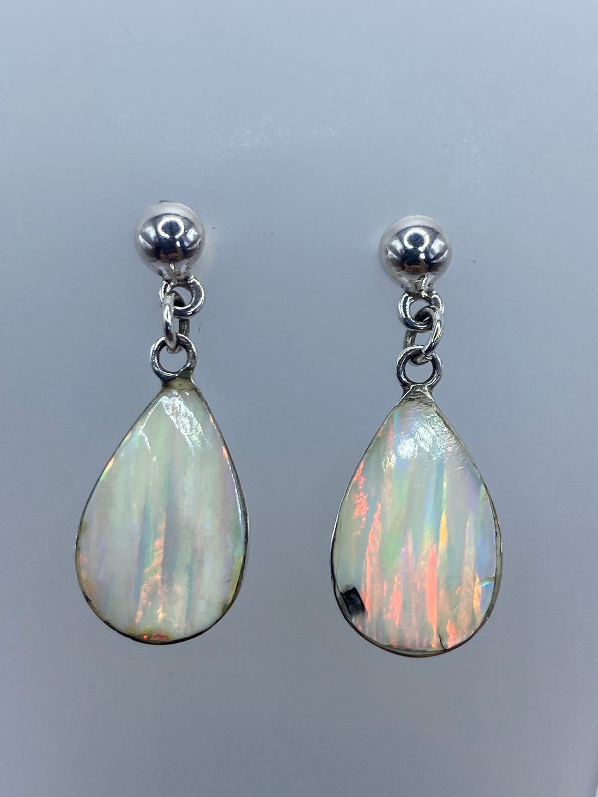 Par de aretes de plata 925 con ópalo de fuego blanco engastado, mostrando destellos de color