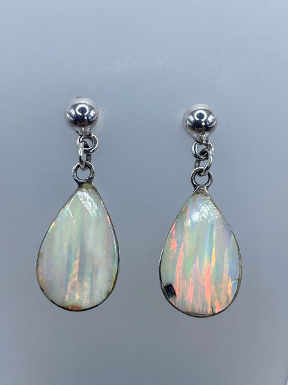 Par de aretes de plata 925 con ópalo de fuego blanco engastado, mostrando destellos de color