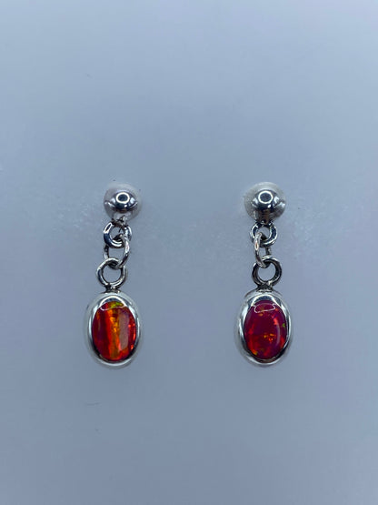 Aretes colgantes con ópalo de fuego rosa mostrando destellos de luz en cada piedra