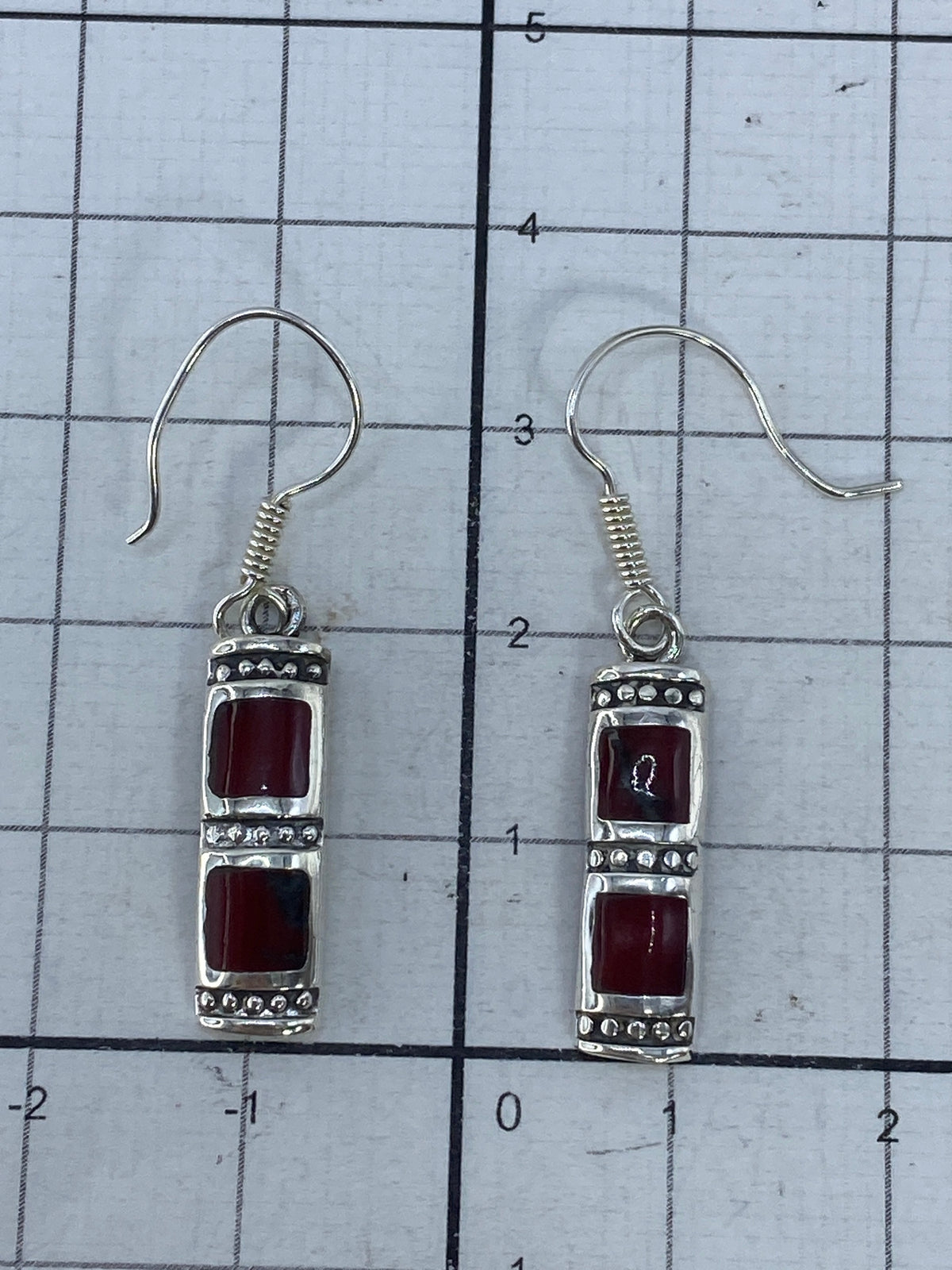 Aretes de plata con coral rojo puesto en la oreja, vista de cómo se ven en uso