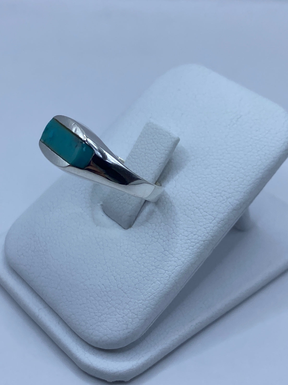 Detalle lateral del anillo mostrando el engaste de turquesa y la banda de plata pulida
