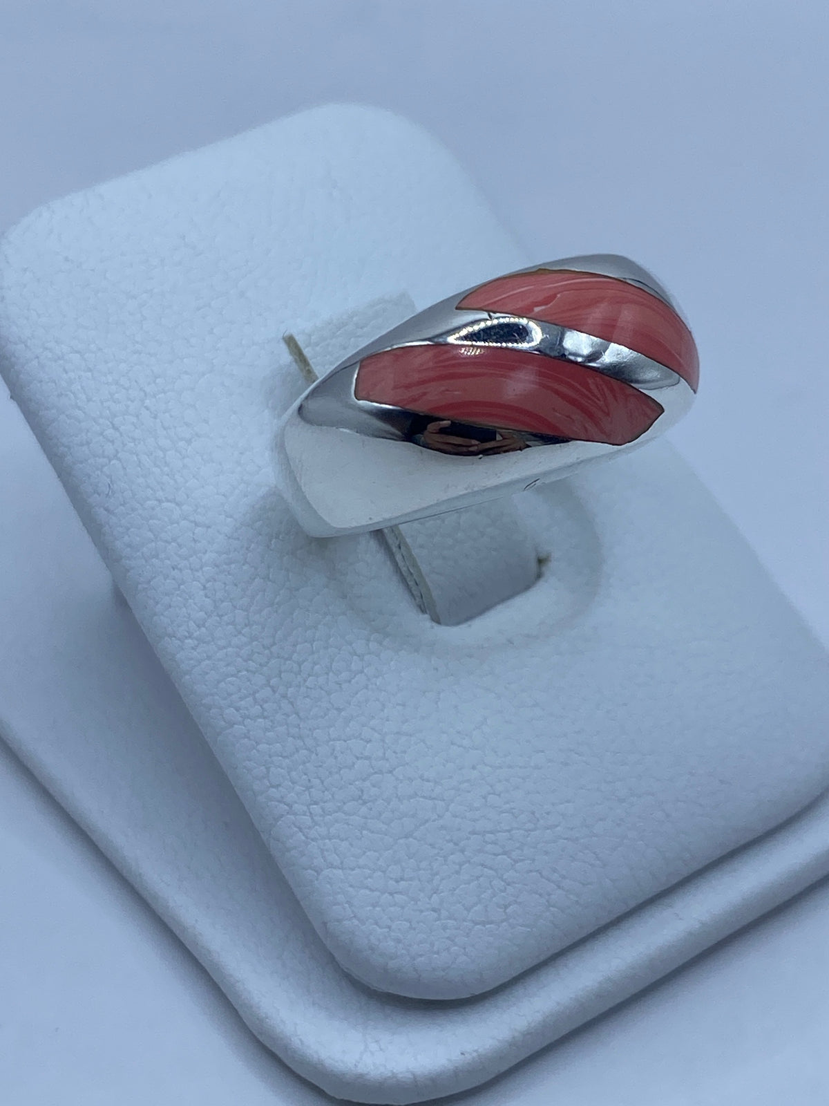 Anillo de plata con coral en la mano, mostrando el engaste a mano y los detalles del metal pulido