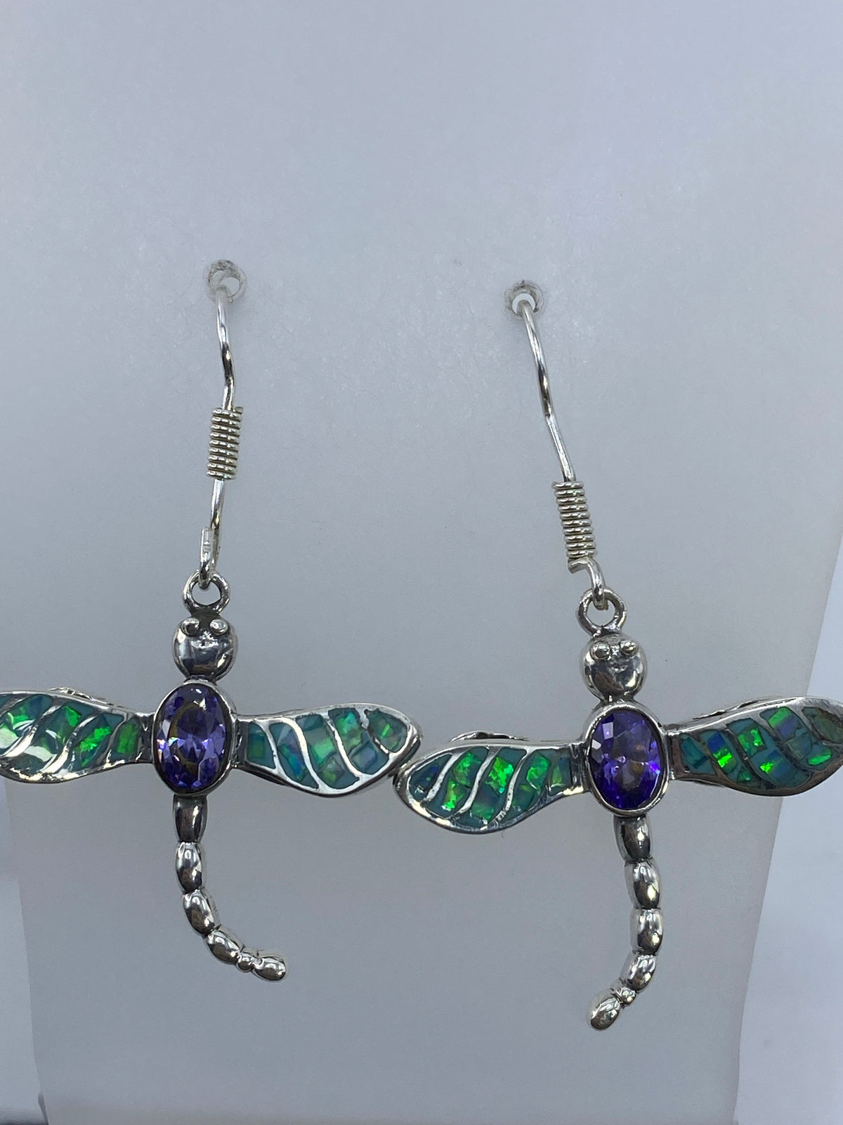 Par de aretes de plata en forma de libélula con ópalo de fuego verde olivo y circonia morada colgando