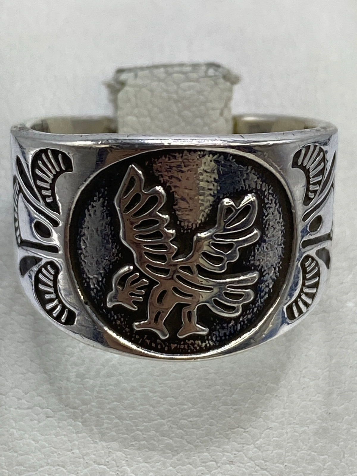 Anillo de plata repujado en la mano, mostrando la profundidad del diseño del águila