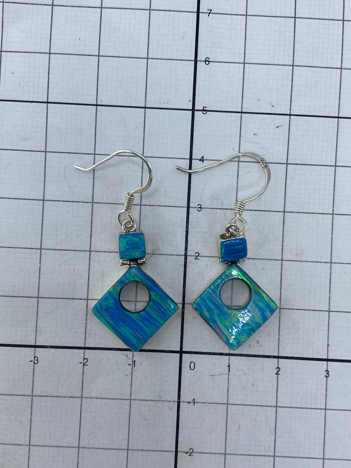 Aretes sobre fondo blanco con hallmark 950 visible en la plata
