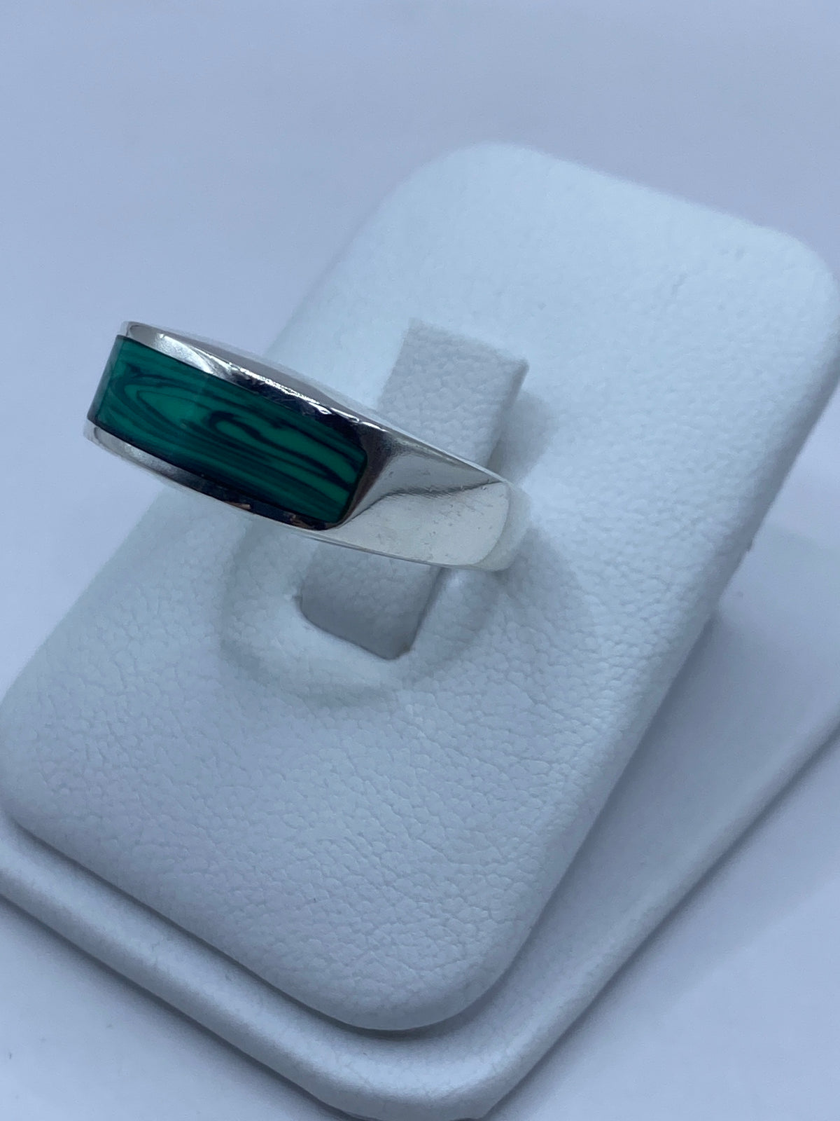 Detalle lateral del anillo mostrando el engaste a mano de la malaquita y las vetas naturales